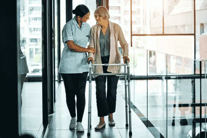 Caregiver assisting a senior woman with a walker, symbolizing specialized and extended care services, including elderly care and daily living assistance. {{brizy_dc_image_alt imageSrc=